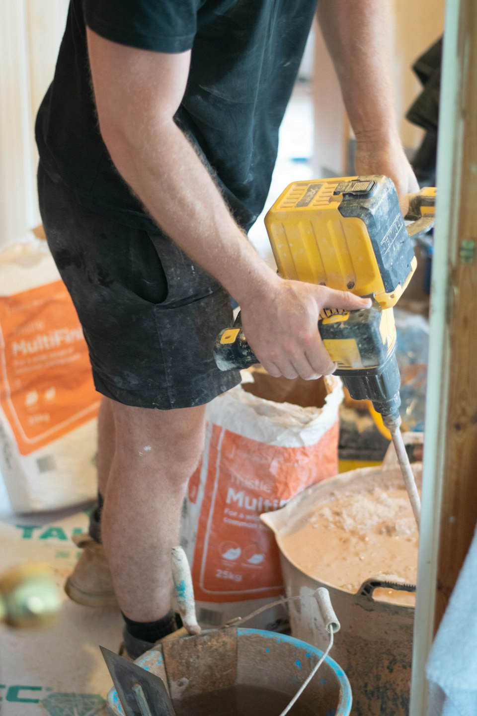 Operaio edile mescola intonaco in un secchio in un cantiere di ristrutturazione.